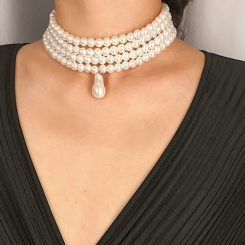 Pearl necklace with a drop pendant worn by a person in a black dress.