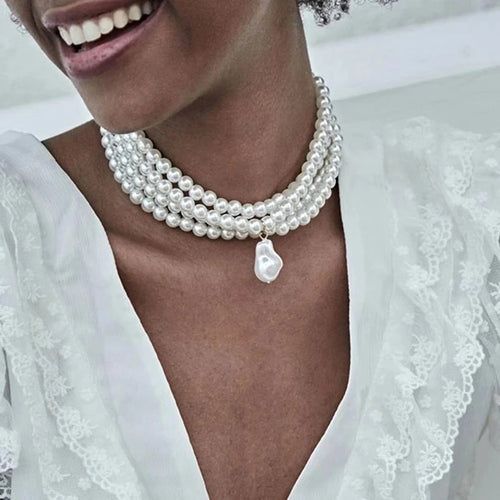 Close-up of a woman wearing a pearl necklace with a white lace garment.